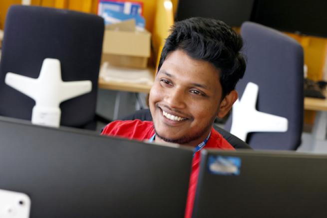 Man sits at desk with two computer screens in front of him 