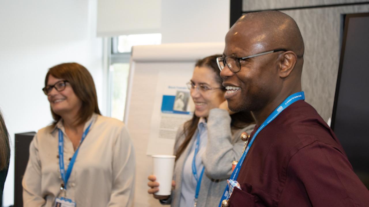 Three people standing in an office with a flipchart in the background 