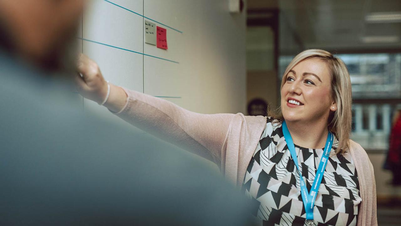 Woman points at board smiling 