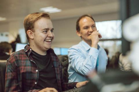 Two men looking at a computer screen smiling