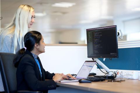 Woman sits at desk looking at computer screen