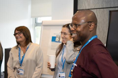 Three people standing in an office with a flipchart in the background 